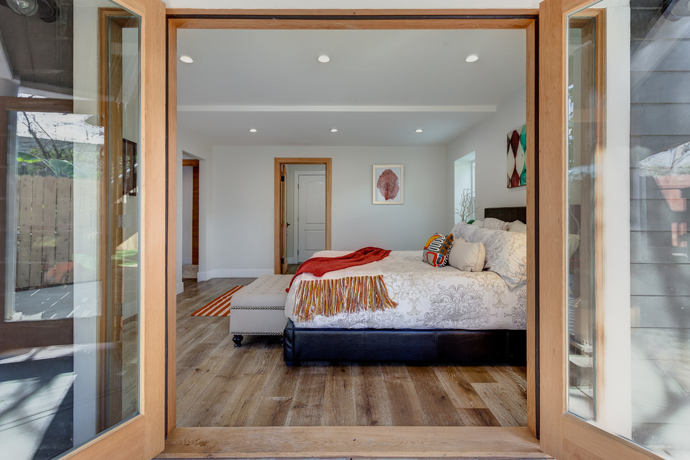 This is an example of a mid-sized contemporary master bedroom in Los Angeles with white walls, light hardwood floors, no fireplace and brown floor.