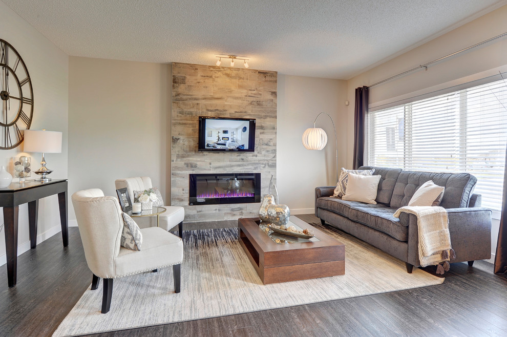 Photo of a mid-sized transitional formal open concept living room in Edmonton with grey walls, vinyl floors, a hanging fireplace, a tile fireplace surround, a wall-mounted tv and black floor.