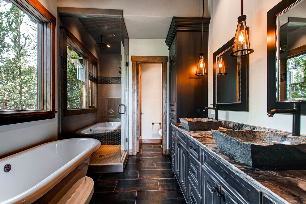 Photo of a country bathroom in Denver with a freestanding tub, black cabinets and beige floor.