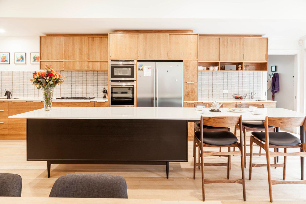 Photo of a large midcentury galley open plan kitchen in Melbourne with with island, quartz benchtops, an undermount sink, beige splashback, ceramic splashback, stainless steel appliances, flat-panel cabinets, light wood cabinets, light hardwood floors and beige floor.