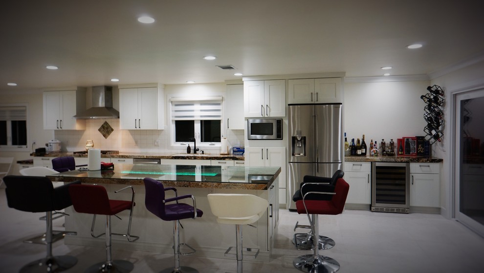Inspiration for a mid-sized transitional l-shaped gray floor enclosed kitchen remodel in Orange County with an undermount sink, shaker cabinets, white cabinets, granite countertops, white backsplash, ceramic backsplash, stainless steel appliances and an island