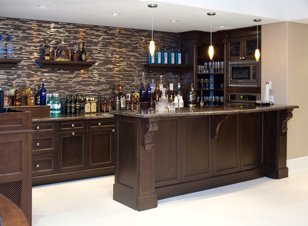 Photo of a large transitional single-wall wet bar in Toronto with an undermount sink, shaker cabinets, dark wood cabinets, granite benchtops, black splashback, glass tile splashback, limestone floors, beige floor and multi-coloured benchtop.