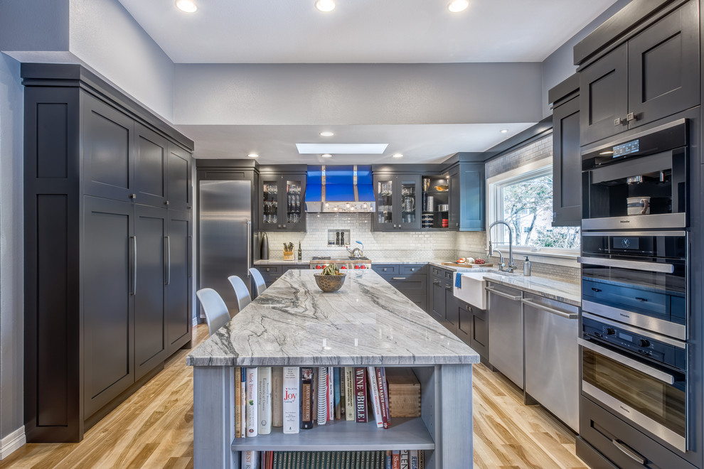 Inspiration for a large transitional u-shaped light wood floor eat-in kitchen remodel in Denver with a farmhouse sink, recessed-panel cabinets, gray cabinets, quartzite countertops, blue backsplash, ceramic backsplash, stainless steel appliances and an island