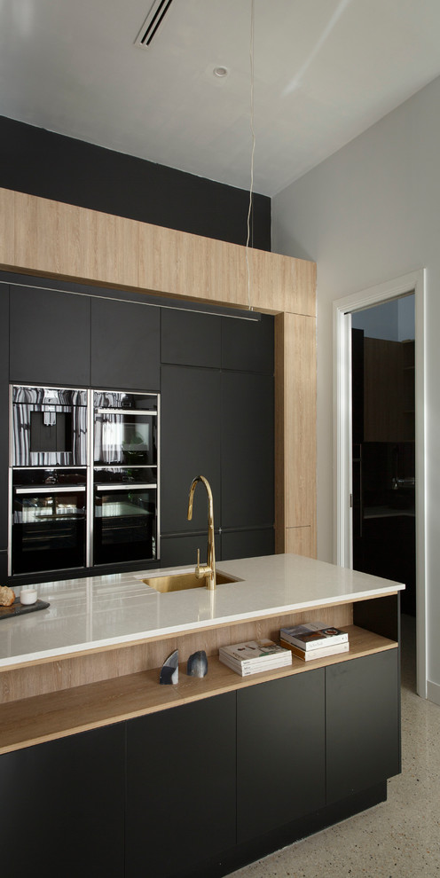 Photo of a large modern galley kitchen pantry in Melbourne with a single-bowl sink, black cabinets, quartz benchtops, metallic splashback, mirror splashback, black appliances and with island.