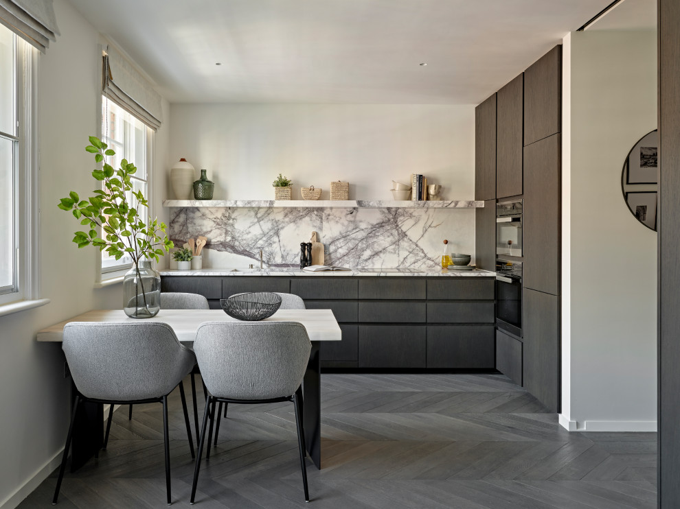 Design ideas for a mid-sized contemporary l-shaped eat-in kitchen in London with flat-panel cabinets, dark wood cabinets, marble benchtops, marble splashback, panelled appliances, dark hardwood floors, no island, an integrated sink, grey floor and white benchtop.