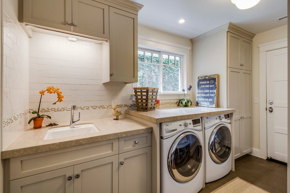 Inspiration for a mid-sized transitional galley utility room in Los Angeles with shaker cabinets, limestone benchtops, a side-by-side washer and dryer, an undermount sink, beige walls, ceramic floors and grey cabinets.
