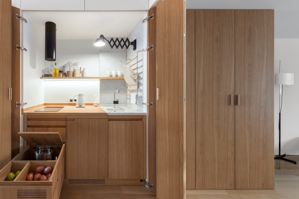 Inspiration for a small contemporary separate kitchen in Moscow with an undermount sink, medium wood cabinets, wood benchtops, white splashback, panelled appliances and medium hardwood floors.