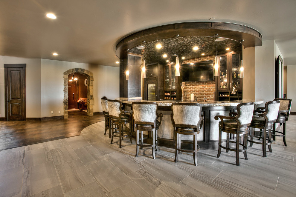 Inspiration for an expansive country single-wall seated home bar in Denver with an undermount sink, shaker cabinets, dark wood cabinets, granite benchtops, red splashback, stone tile splashback and slate floors.