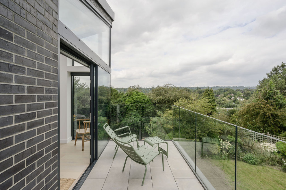 Example of a small trendy glass railing balcony design in Surrey with no cover