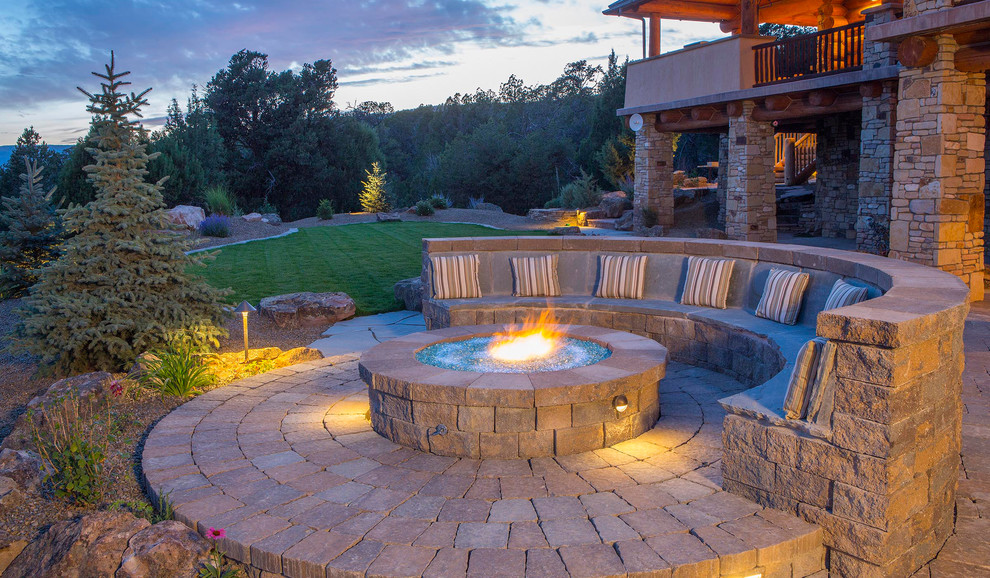 Design ideas for a large country backyard patio in Denver with a fire feature, natural stone pavers and no cover.