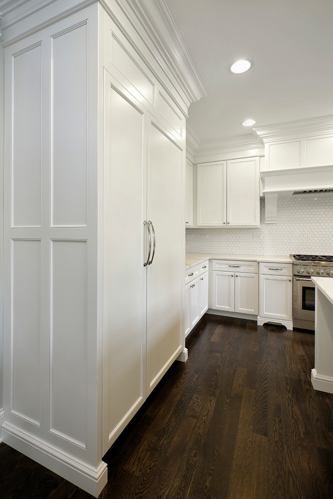 Inspiration for a large traditional u-shaped eat-in kitchen in Chicago with a farmhouse sink, recessed-panel cabinets, white cabinets, quartz benchtops, white splashback, mosaic tile splashback, stainless steel appliances, dark hardwood floors, with island and brown floor.