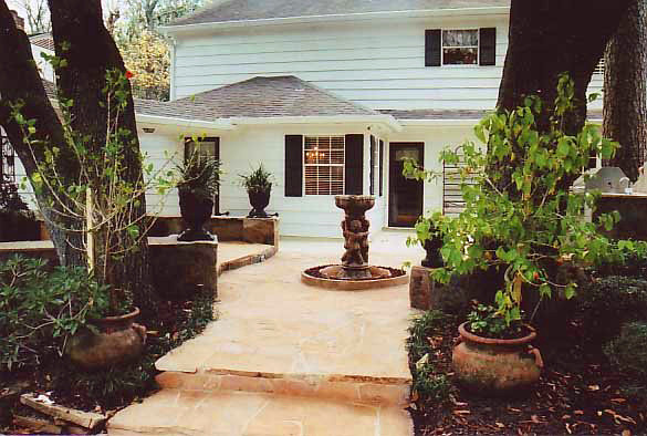 This is an example of a mid-sized mediterranean backyard partial sun garden in Houston with a water feature and natural stone pavers.