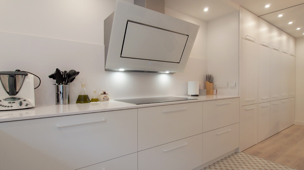 Photo of a large contemporary l-shaped open plan kitchen in Barcelona with an undermount sink, flat-panel cabinets, white cabinets, solid surface benchtops, white splashback, ceramic splashback, stainless steel appliances, cement tiles and multi-coloured floor.
