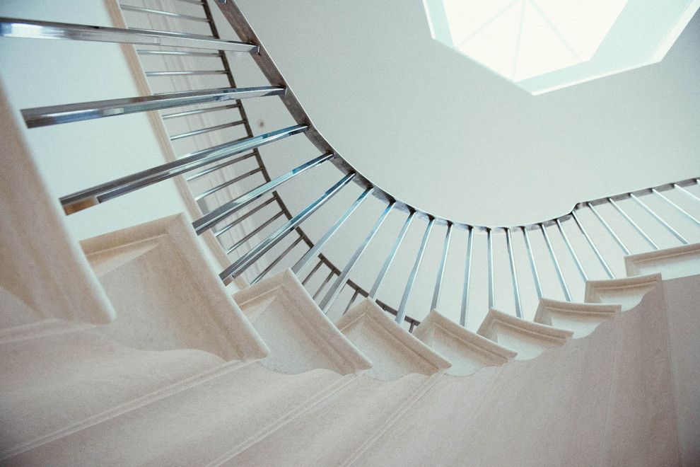 Стильный дизайн: п-образная лестница в классическом стиле с ступенями из известняка, подступенками из известняка и металлическими перилами - последний тренд