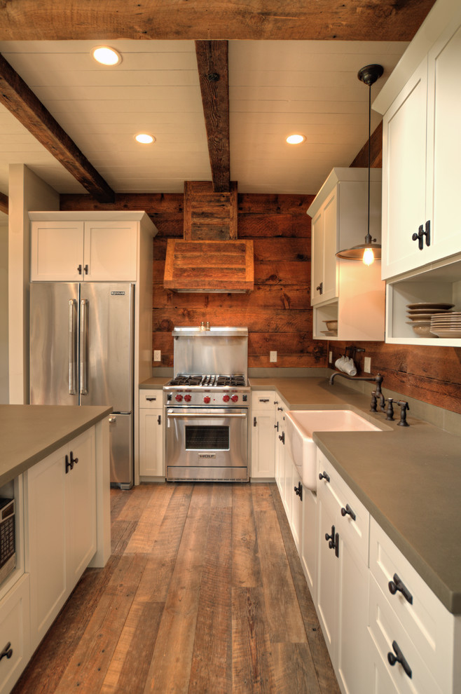 This is an example of a mid-sized traditional l-shaped open plan kitchen in Seattle with a farmhouse sink, shaker cabinets, white cabinets, concrete benchtops, timber splashback, stainless steel appliances, dark hardwood floors and with island.