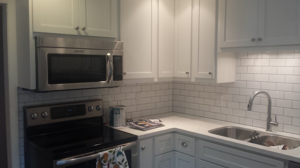 U-shaped eat-in kitchen photo with an undermount sink, shaker cabinets, white cabinets, white backsplash, subway tile backsplash and stainless steel appliances