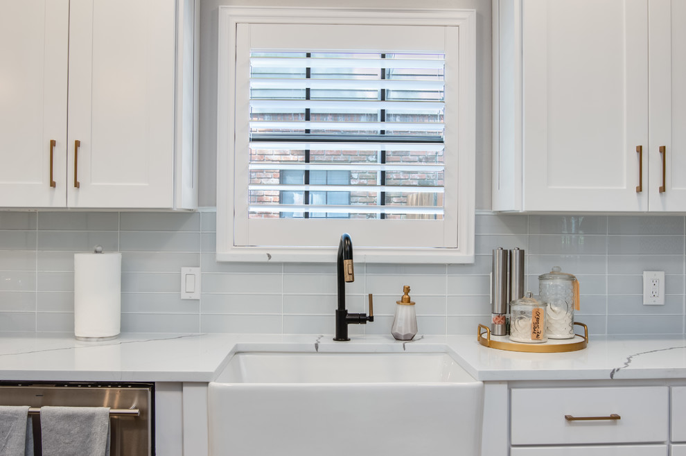 Kitchen pantry - large transitional l-shaped porcelain tile and gray floor kitchen pantry idea in Houston with a farmhouse sink, shaker cabinets, white cabinets, quartzite countertops, white backsplash, glass tile backsplash, stainless steel appliances, an island and white countertops
