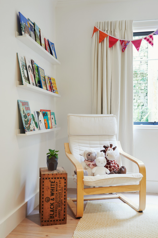 Photo of a contemporary gender-neutral kids' room in Wellington with white walls and light hardwood floors.