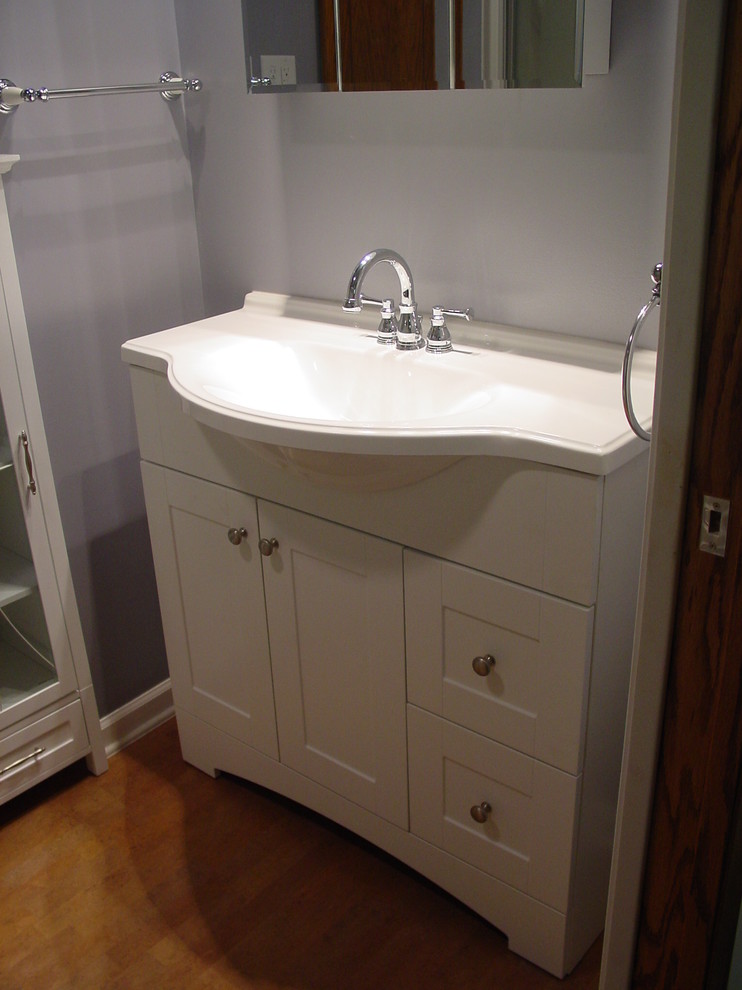 Inspiration for a small traditional bathroom in Minneapolis with an integrated sink, flat-panel cabinets, white cabinets, marble benchtops, a drop-in tub, a shower/bathtub combo, a two-piece toilet, blue walls and light hardwood floors.
