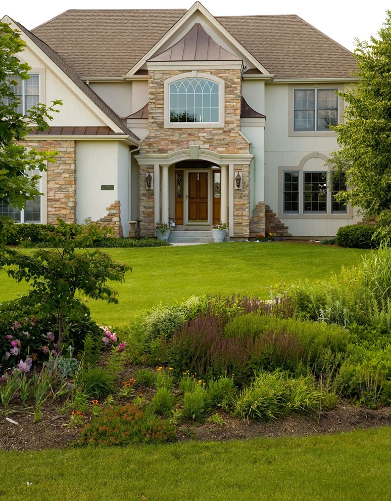 Large traditional two-storey beige exterior in Chicago with stone veneer.