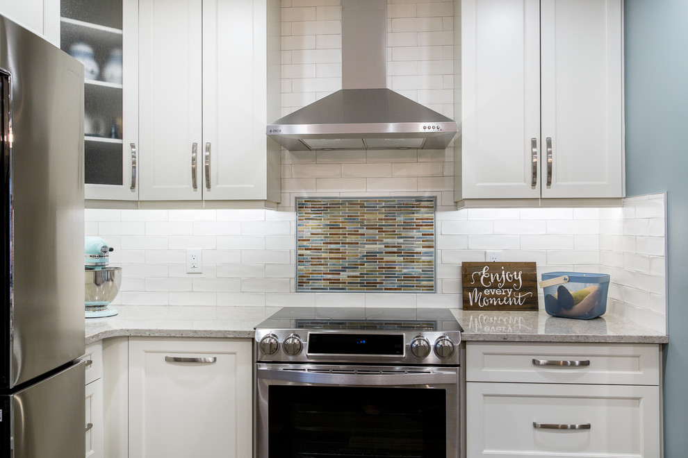 Inspiration for a transitional l-shaped medium tone wood floor eat-in kitchen remodel in Edmonton with an undermount sink, shaker cabinets, white cabinets, quartz countertops, white backsplash, porcelain backsplash, stainless steel appliances and an island