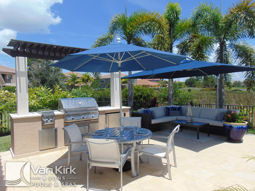 Photo of a mid-sized contemporary backyard patio in Miami with an outdoor kitchen, natural stone pavers and a pergola.
