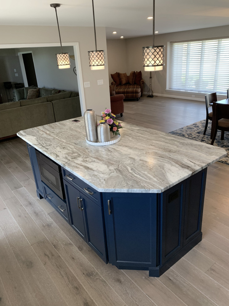 Large transitional l-shaped vinyl floor and gray floor eat-in kitchen photo with an undermount sink, recessed-panel cabinets, white cabinets, quartz countertops, gray backsplash, ceramic backsplash, stainless steel appliances, an island and white countertops