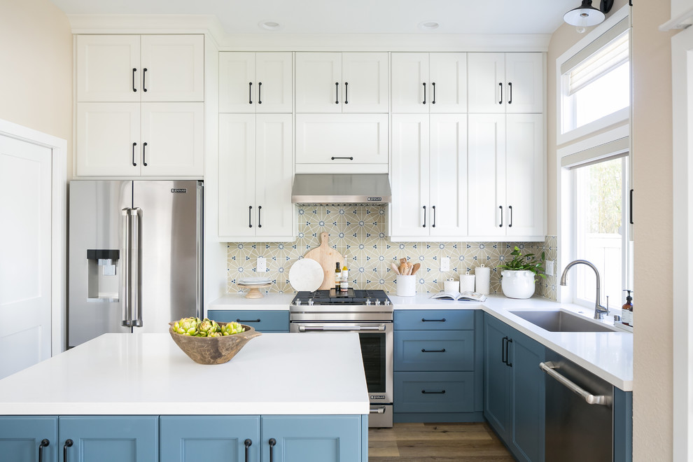 Inspiration for a transitional u-shaped kitchen in San Diego with beaded inset cabinets, white cabinets, quartz benchtops, multi-coloured splashback, porcelain splashback, stainless steel appliances, medium hardwood floors, with island and white benchtop.