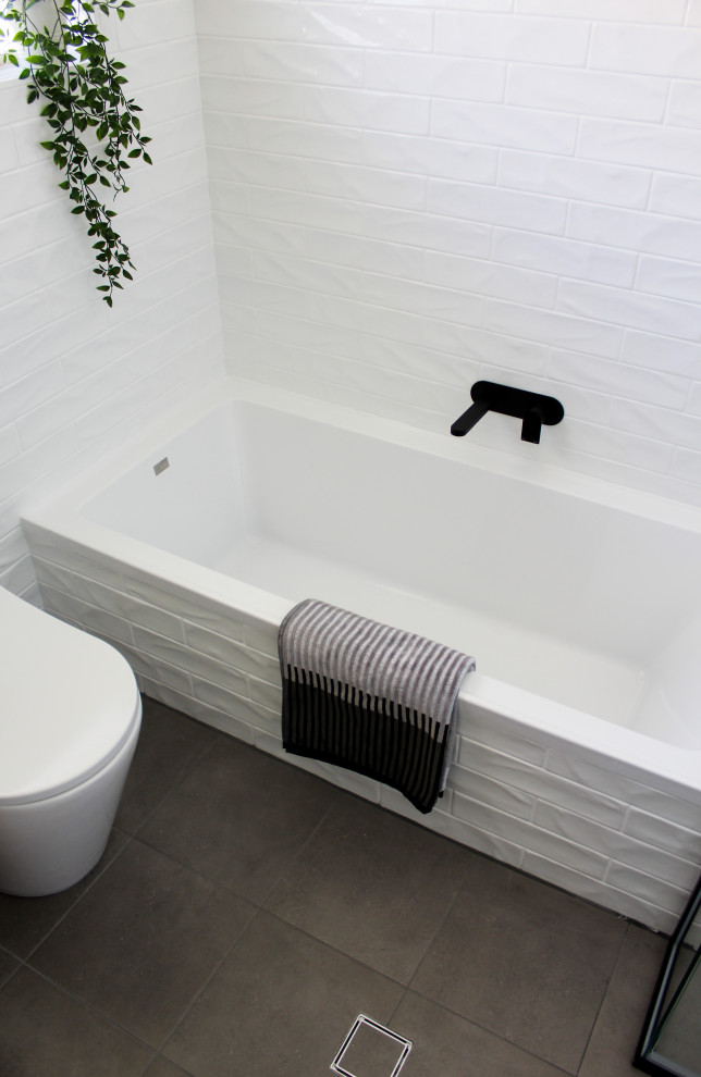 This is an example of a small modern master bathroom in Perth with flat-panel cabinets, dark wood cabinets, a drop-in tub, a corner shower, a one-piece toilet, white tile, ceramic tile, white walls, porcelain floors, a vessel sink, engineered quartz benchtops, grey floor, a hinged shower door and white benchtops.