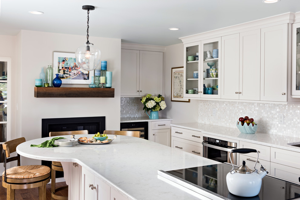 This is an example of a mid-sized beach style galley separate kitchen in Boston with an undermount sink, shaker cabinets, white cabinets, quartzite benchtops, white splashback, mosaic tile splashback, stainless steel appliances, medium hardwood floors, with island and brown floor.