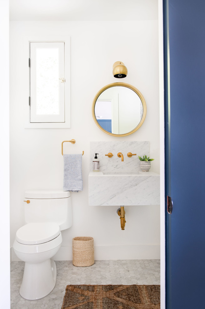 Inspiration for a mid-sized transitional powder room in Los Angeles with a two-piece toilet, white walls, marble floors, a wall-mount sink, marble benchtops, grey floor and white benchtops.