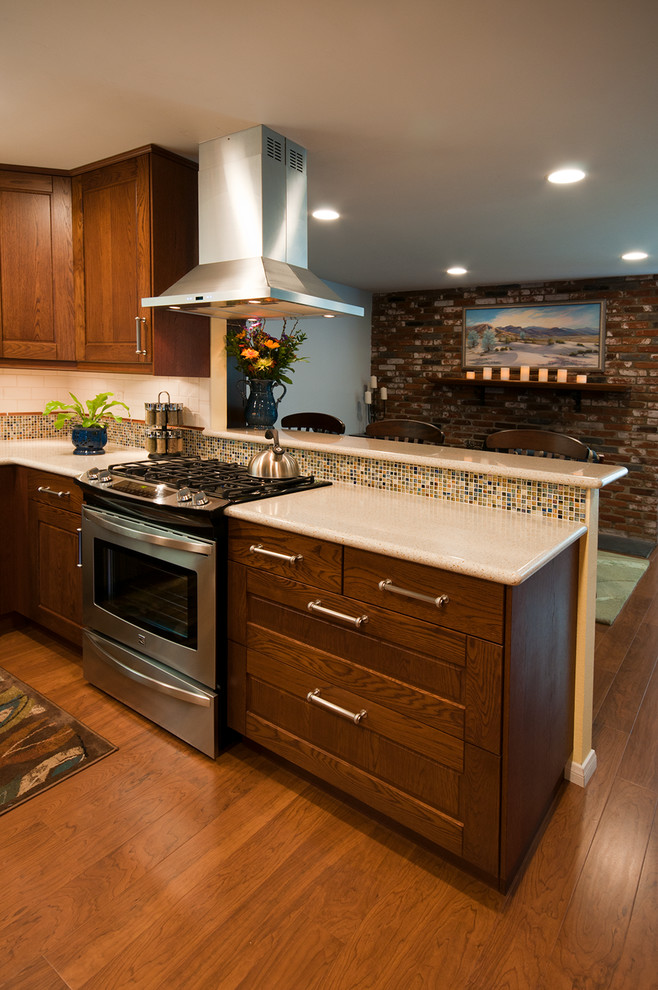 Mid-sized transitional u-shaped medium tone wood floor eat-in kitchen photo in San Diego with an integrated sink, medium tone wood cabinets, solid surface countertops, stainless steel appliances, raised-panel cabinets, multicolored backsplash, mosaic tile backsplash and a peninsula