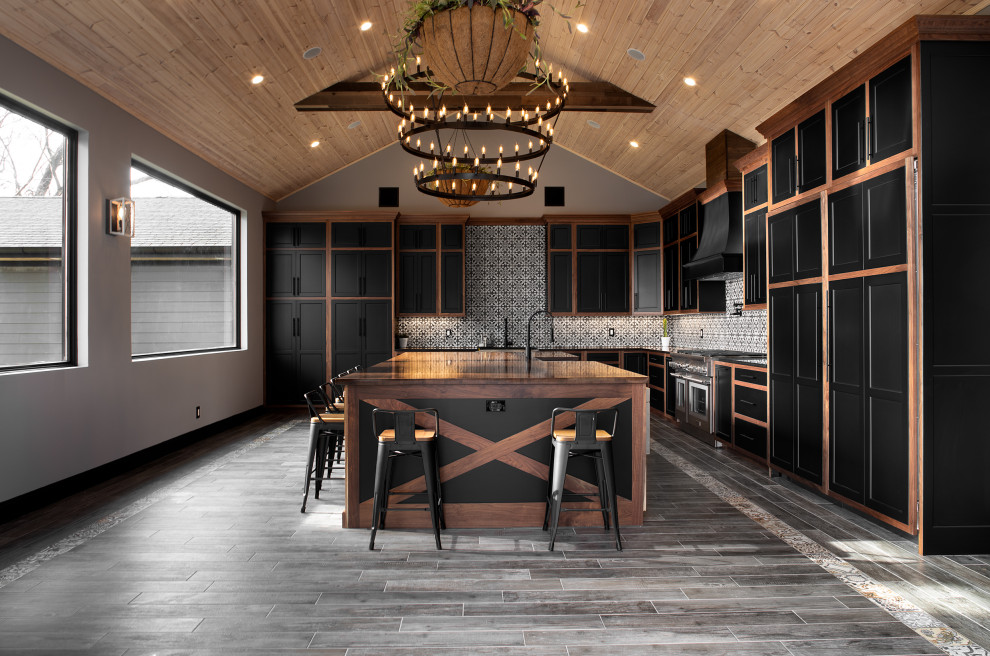 Photo of a large contemporary l-shaped kitchen/diner in New York with shaker cabinets, black cabinets, white splashback, mosaic tiled splashback, stainless steel appliances, ceramic flooring, an island, grey floors, black worktops and a vaulted ceiling.