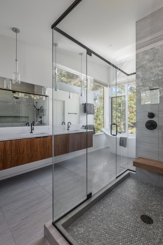 Photo of a mid-sized contemporary master bathroom in Charleston with flat-panel cabinets, dark wood cabinets, a freestanding tub, a corner shower, gray tile, porcelain tile, white walls, porcelain floors and an undermount sink.