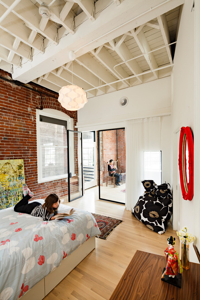 Photo of an industrial kids' bedroom for girls in Portland with white walls and light hardwood floors.