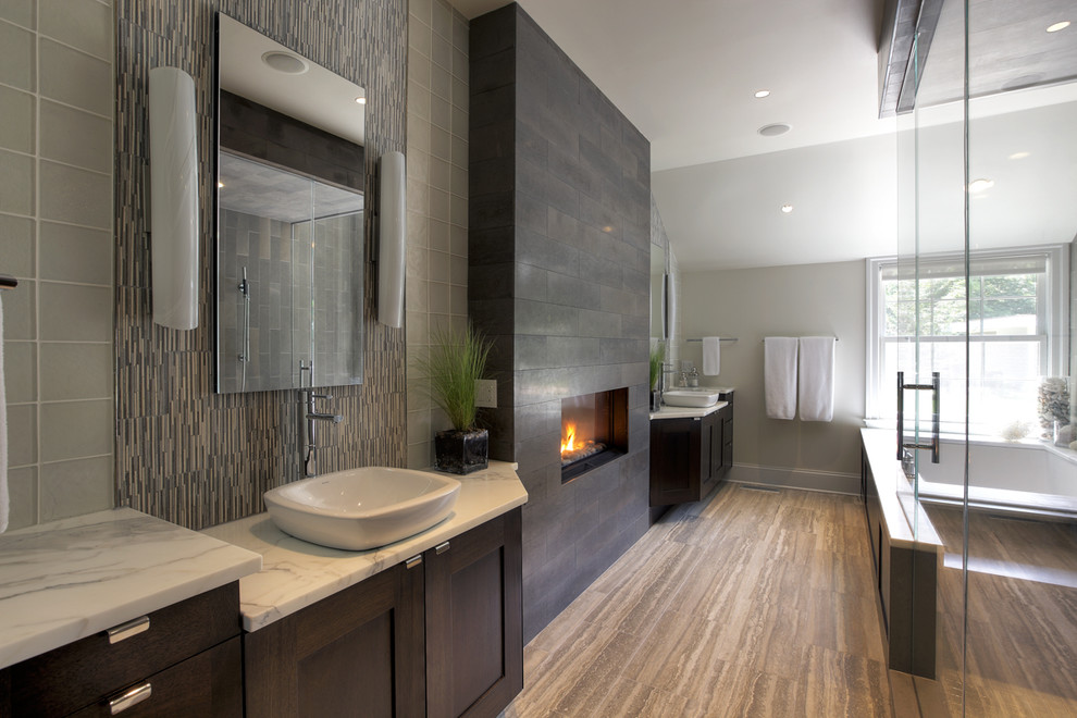 Large trendy gray tile dark wood floor bathroom photo in New York with a vessel sink, shaker cabinets, dark wood cabinets, an undermount tub and white walls