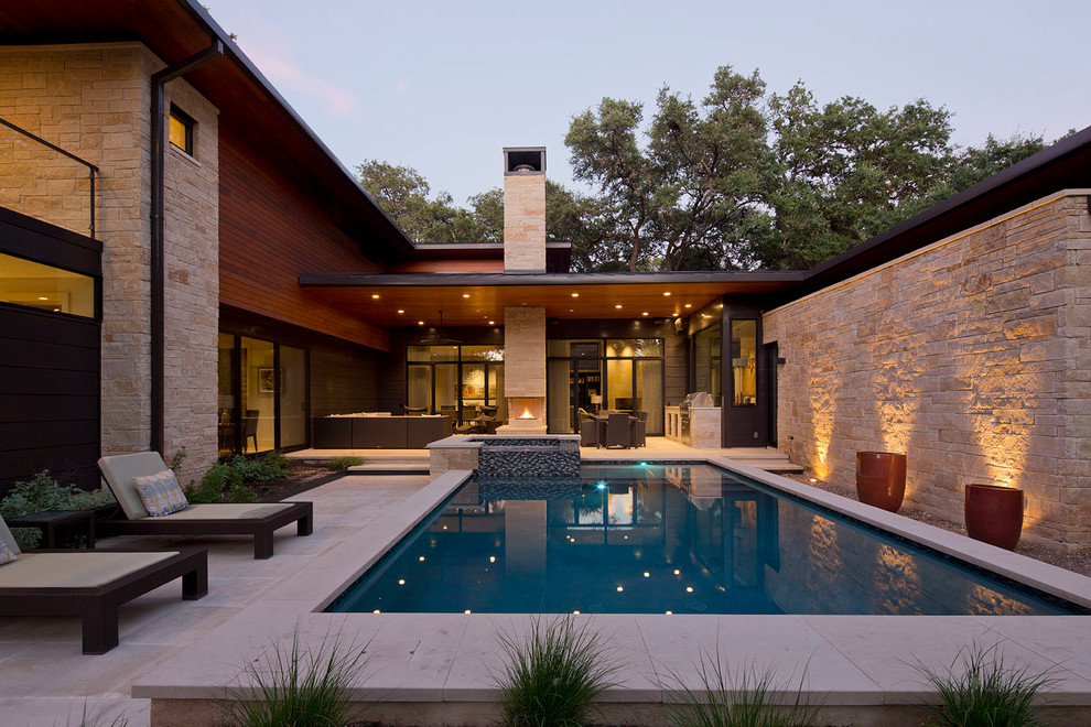 This is an example of a contemporary backyard rectangular pool in Austin with a hot tub and natural stone pavers.