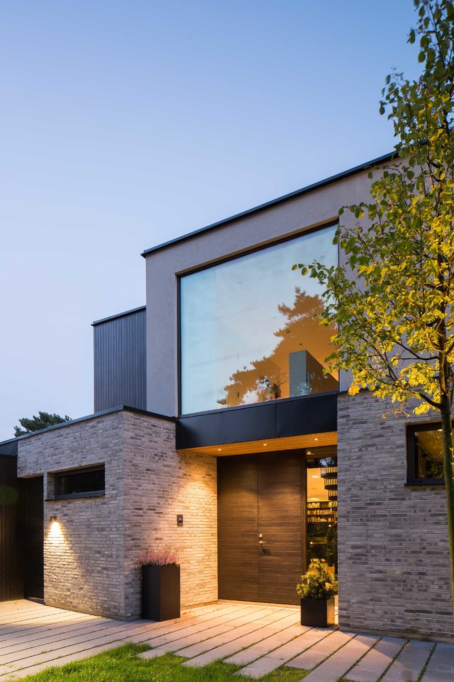 This is an example of a large contemporary two-storey beige exterior in Malmo with stone veneer and a flat roof.