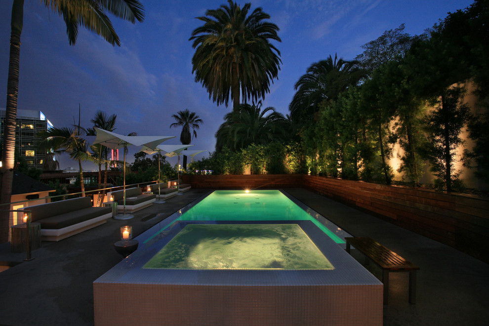 Photo of a large contemporary backyard rectangular infinity pool in Los Angeles with a hot tub and concrete slab.