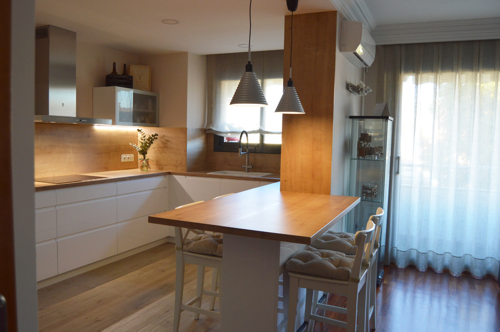 This is an example of a large scandinavian u-shaped eat-in kitchen in Barcelona with a farmhouse sink, flat-panel cabinets, white cabinets, laminate benchtops, brown splashback, timber splashback, stainless steel appliances, ceramic floors, a peninsula, brown floor and brown benchtop.