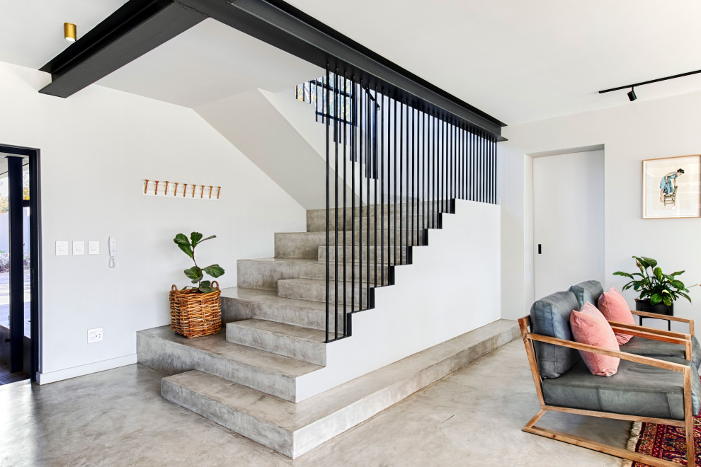 Diseño de escalera en U contemporánea con escalones de hormigón, contrahuellas de hormigón y barandilla de metal