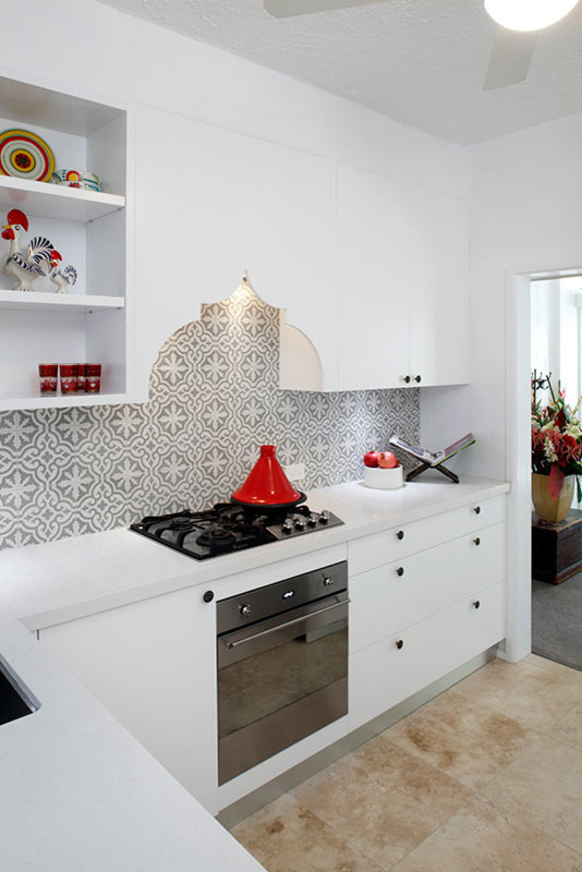 Photo of a small contemporary l-shaped separate kitchen in Sydney with a single-bowl sink, flat-panel cabinets, white cabinets, multi-coloured splashback, ceramic splashback, stainless steel appliances, travertine floors and no island.