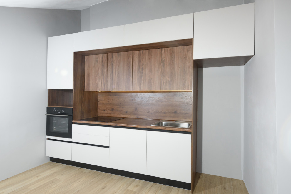 Medium sized contemporary single-wall kitchen/diner in Other with a built-in sink, flat-panel cabinets, white cabinets, wood splashback, black appliances and an island.