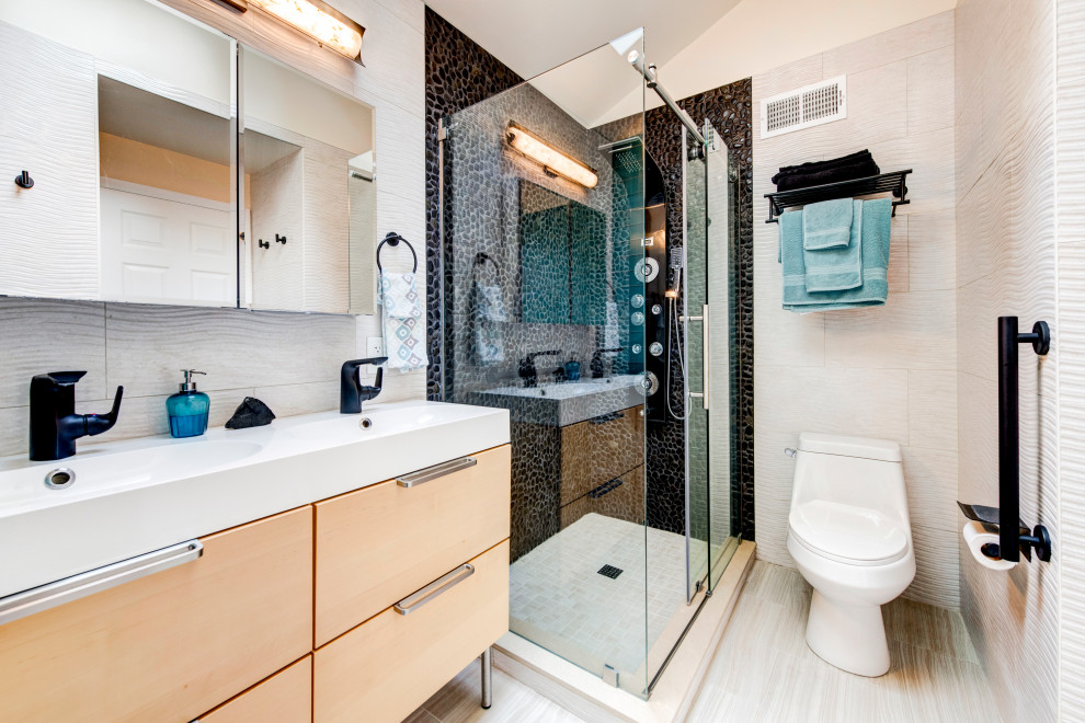 Photo of a mid-sized contemporary master bathroom in DC Metro with flat-panel cabinets, light wood cabinets, an alcove tub, a corner shower, a one-piece toilet, multi-coloured tile, pebble tile, multi-coloured walls, porcelain floors, an integrated sink, solid surface benchtops, a hinged shower door and white benchtops.