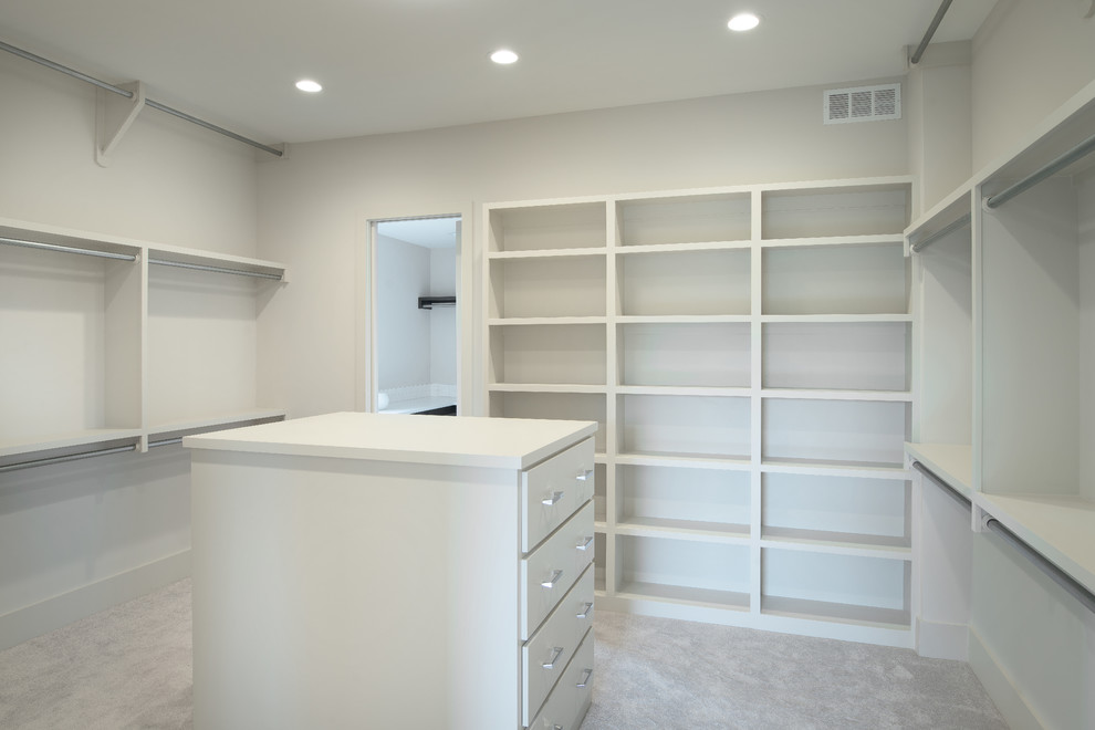 This is an example of a large contemporary gender-neutral walk-in wardrobe in Wichita with flat-panel cabinets, white cabinets and carpet.