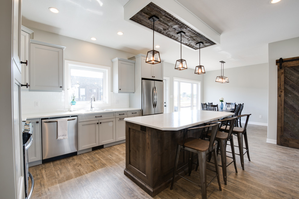 Large transitional l-shaped open concept kitchen photo with shaker cabinets, gray cabinets, laminate countertops, stainless steel appliances and an island