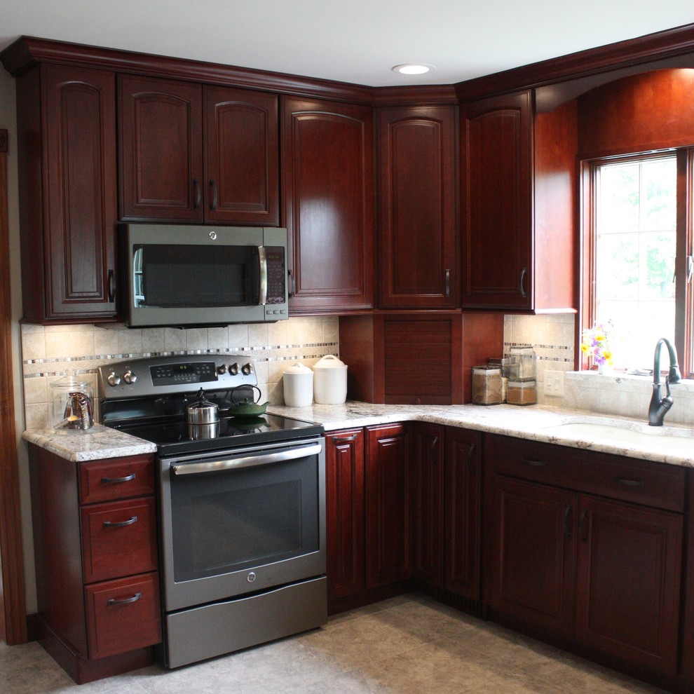 This is an example of a mid-sized traditional u-shaped eat-in kitchen in Other with raised-panel cabinets, medium wood cabinets, granite benchtops, beige splashback and with island.
