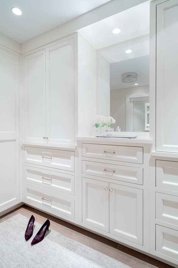 Photo of a large modern gender-neutral dressing room in Philadelphia with white cabinets, medium hardwood floors and brown floor.