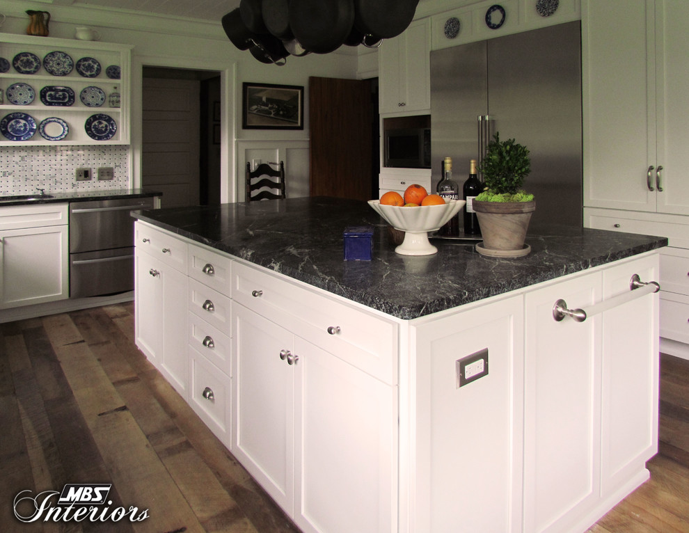 This is an example of a large traditional separate kitchen in Other with a farmhouse sink, white cabinets, grey splashback, stainless steel appliances, dark hardwood floors, with island and recessed-panel cabinets.