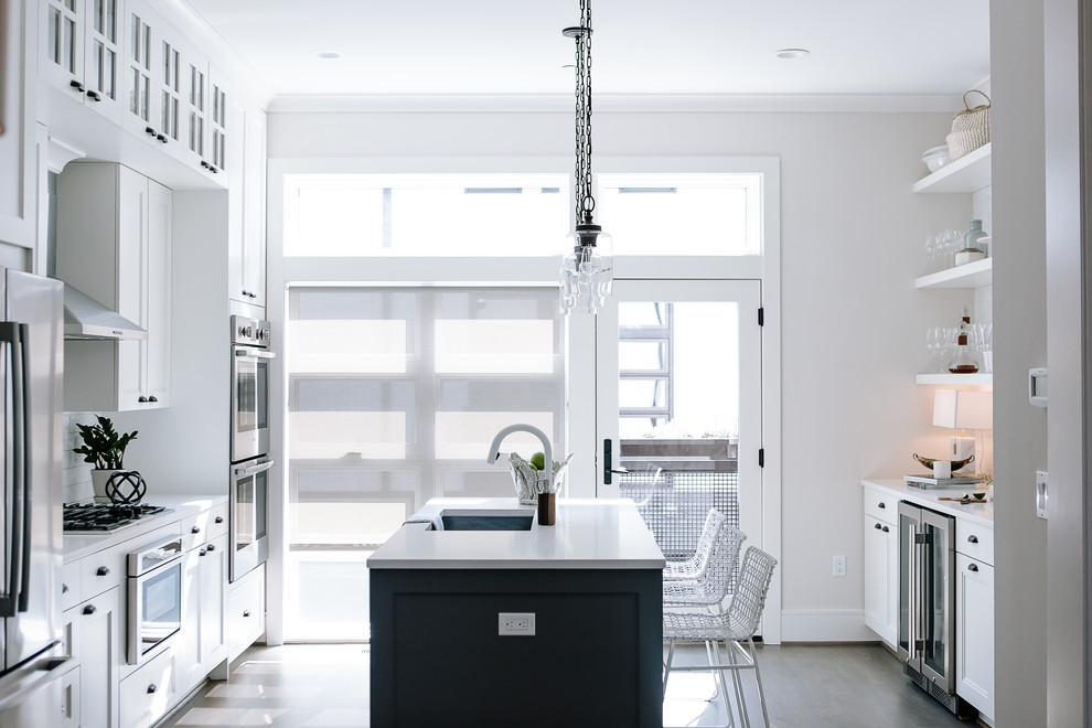 Mid-sized transitional galley dark wood floor and gray floor enclosed kitchen photo in DC Metro with an undermount sink, white cabinets, stainless steel appliances, an island, white countertops, recessed-panel cabinets, solid surface countertops, white backsplash and subway tile backsplash